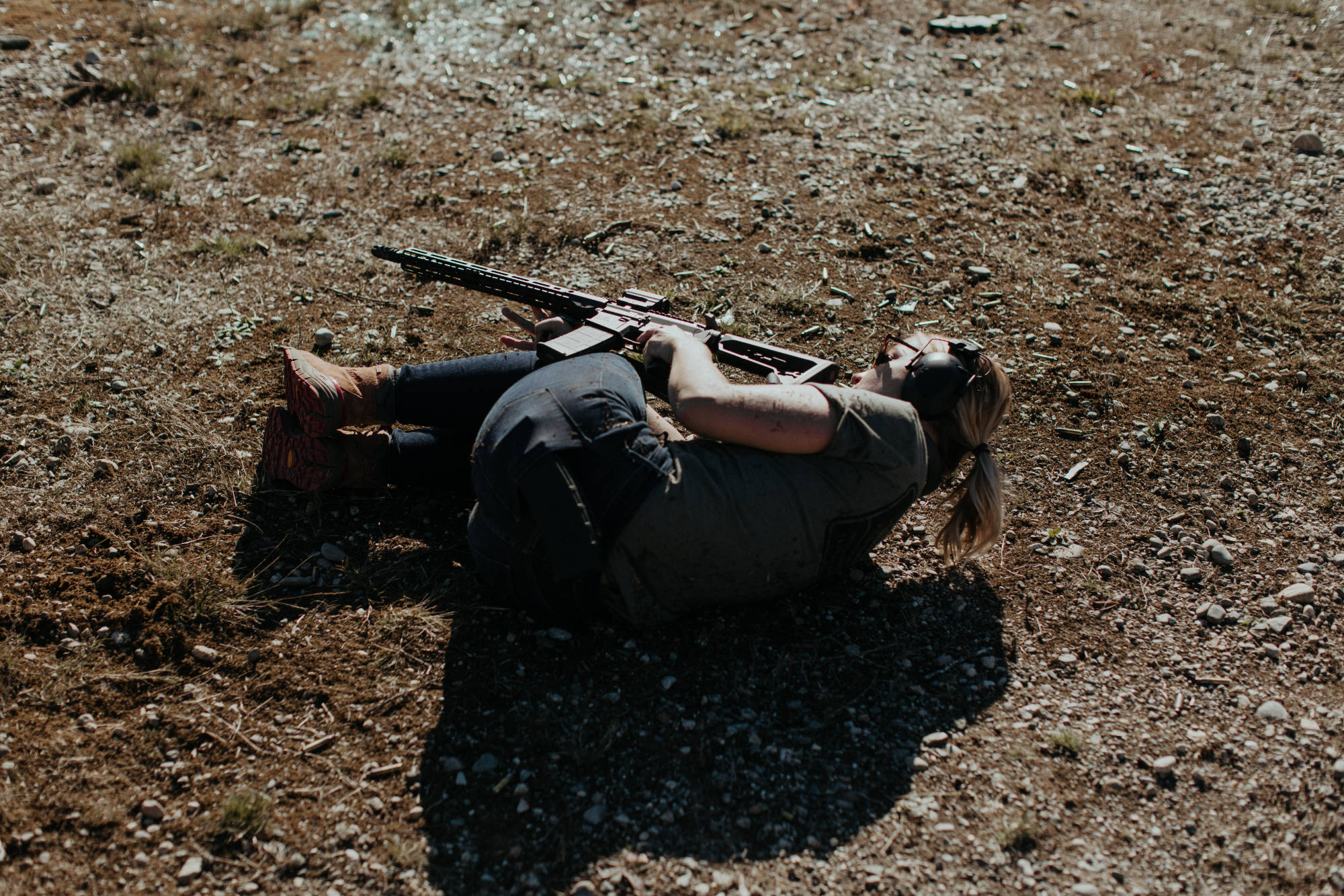 A woman laying on the ground for tactical shooting drill
