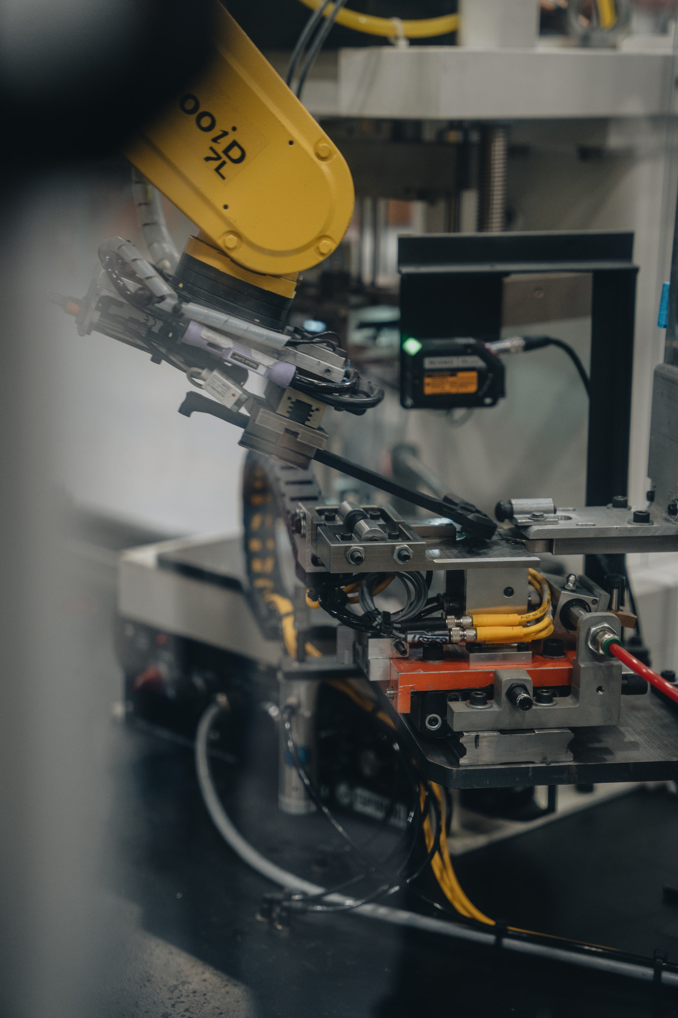 Yellow robot arm assembling an Aero Precision BREACH charging handle